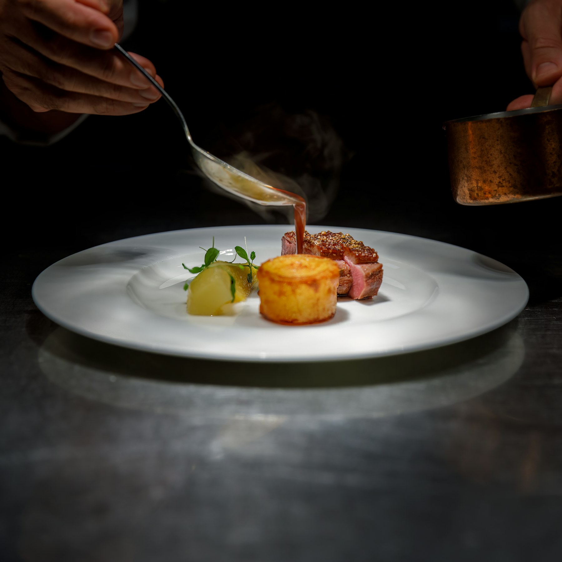 A chef finishing an elegant plated course for private dining service